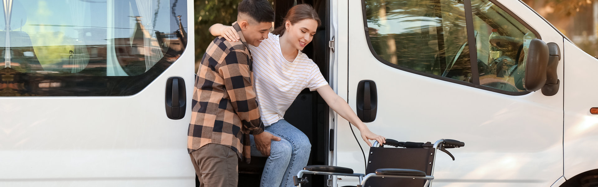 man helping woman with disability getting off the van